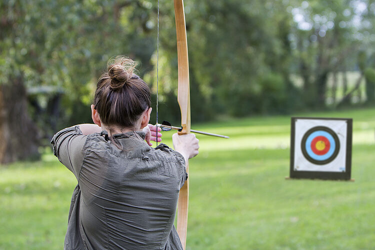 Woman archer to use a bow and arrow and shoot at a target Bogenschießen